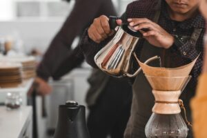 man pouring water in coffee glass